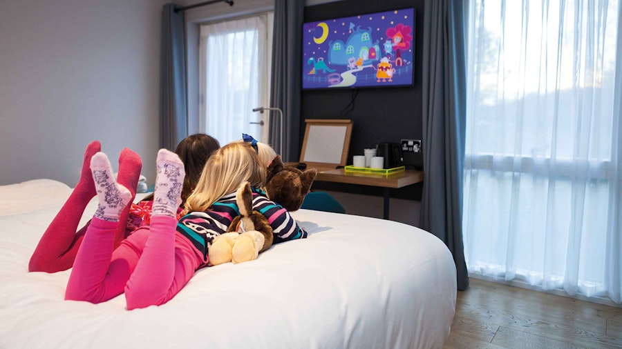 2 little girls watching cartoons in a bedroom