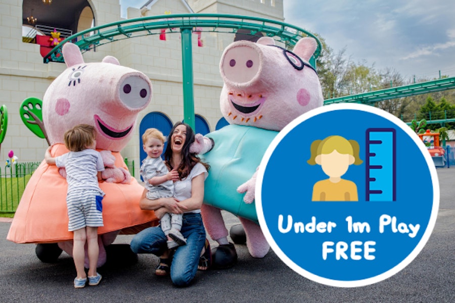 Photo of two animated pig characters interacting with a family outside a building. A badge in the corner reads 'Under 1m Play FREE'.