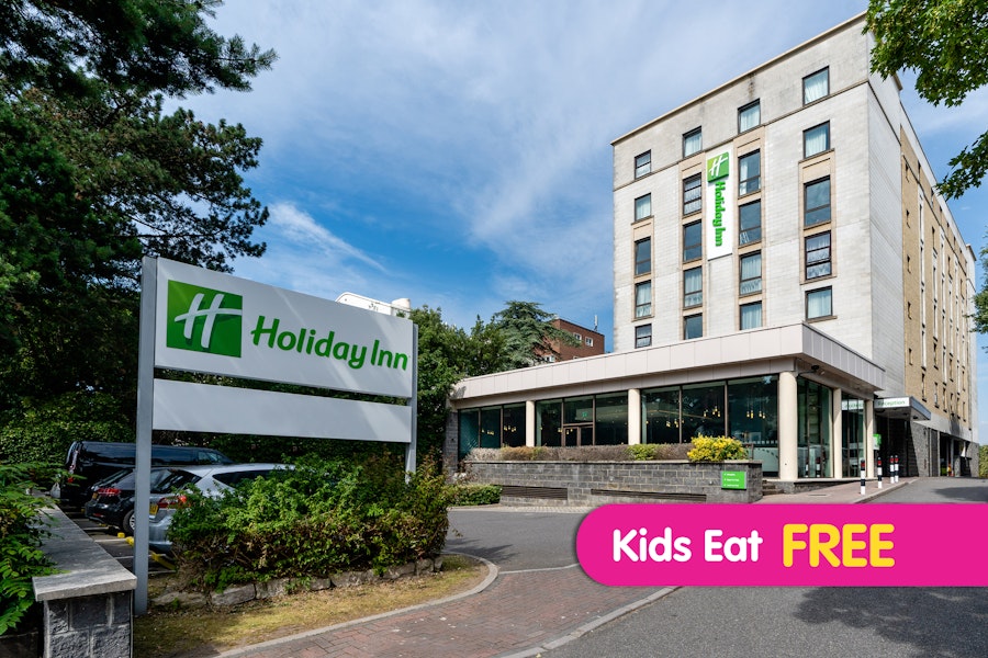 Exterior of Holiday Inn Bournemouth with signage and driveway, blue sky above.