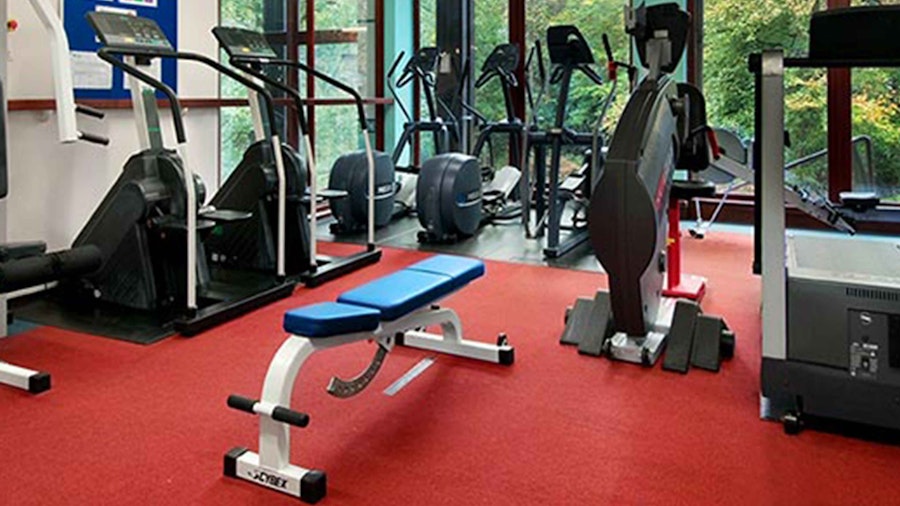 Gym equippment in a room with large wall length windows
